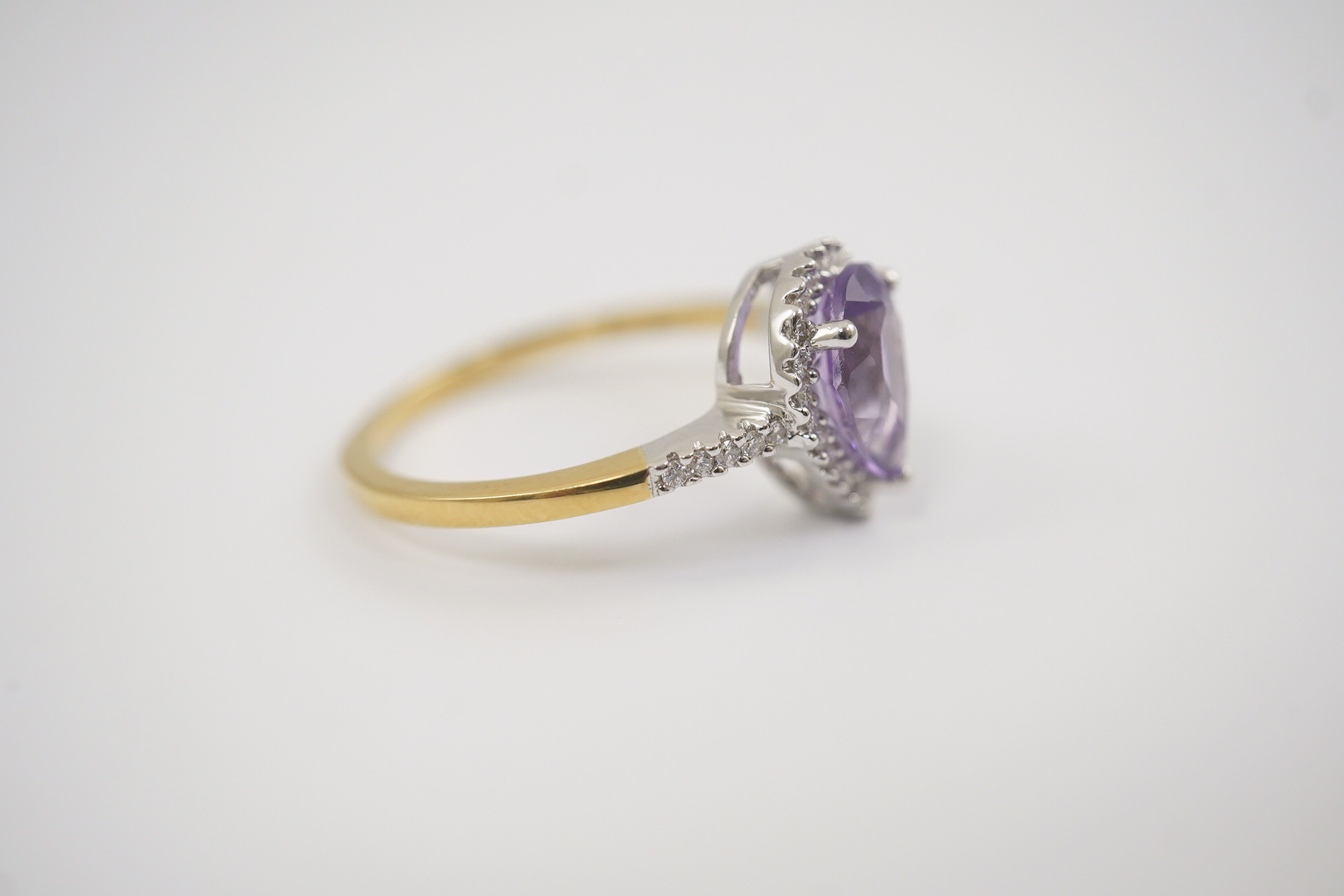 A modern 18ct gold and single stone pear cut amethyst set ring, with diamond chip set border and shoulders, size O, gross weight 3.4 grams. Condition - fair to good